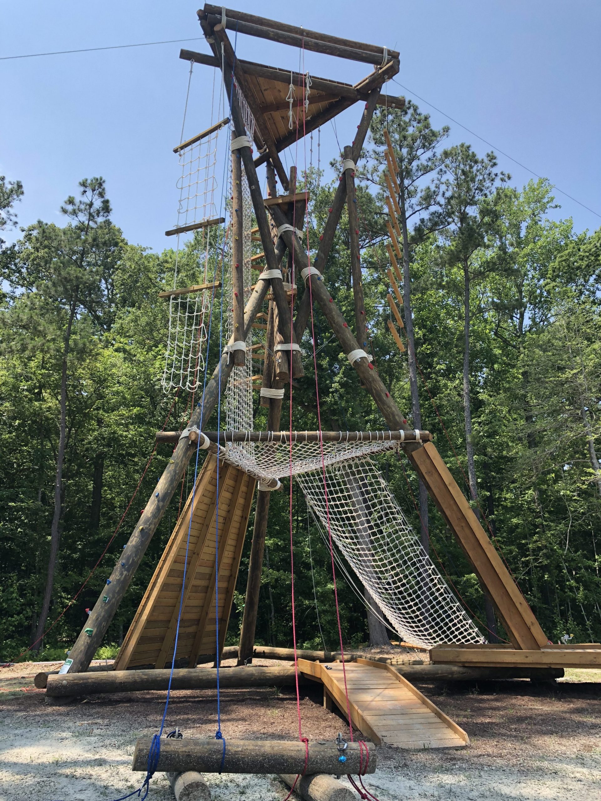 A wooden obstacle tower with rope ladders and climbing walls.